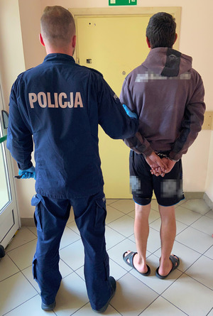 Policjant prowadzi osobę zatrzymaną