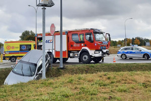 Miejsce zdarzenia drogowego w powiecie gołdapskim. Rozbity samochód w przydrożnym rowie i samochody służb ratunkowych stojące na jezdni
