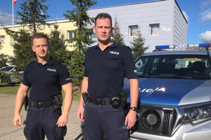 sierż. Piotr Karwowski i st. post. Arkadiusz Sółkowski stojący przed radiowozem