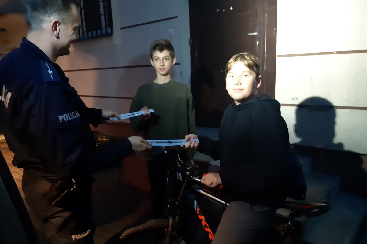 Policjantka podczas rozmowy z mieszkańcami rozdaje im odblaski