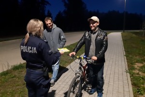 Policjantka podczas rozmowy z mieszkańcami rozdaje im odblaski