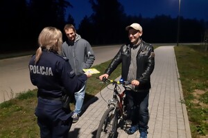 Policjantka podczas rozmowy z mieszkańcami rozdaje im odblaski