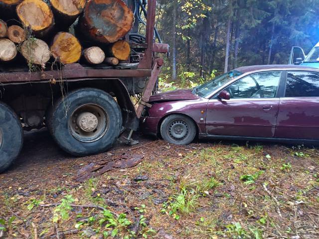 Rozbity samochód osobowy, stojący przy pojeździe ciężarowym, w który uderzył na leśnej drodze