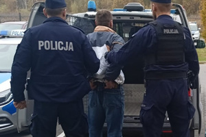 Zatrzymany mężczyzna prowadzony przez policjantów do radiowozu