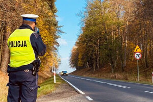 Policjant stoi przy drodze i kontroluje prędkość ręcznym miernikiem