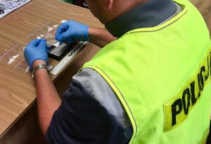 Policjant trzyma w dłoniach zabezpieczone woreczki z narkotykami