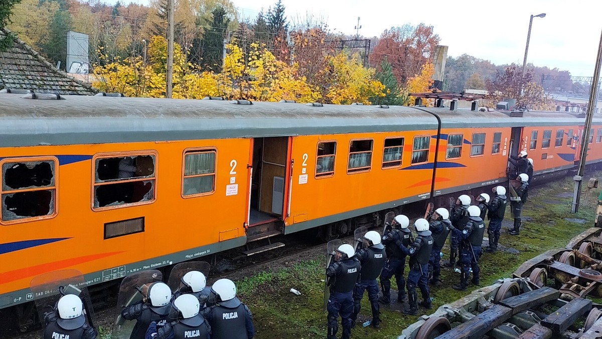 Policjanci biorący udział w ćwiczeniach stojący wzdłuż pociągu