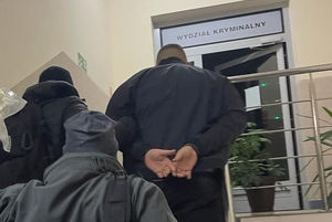 Zatrzymany mężczyzna prowadzony przez policjantów