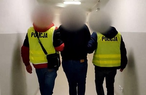 Zatrzymany mężczyzna prowadzony przez policjantów