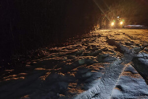 Ślad opony pozostawiony na śniegu i radiowóz w tle