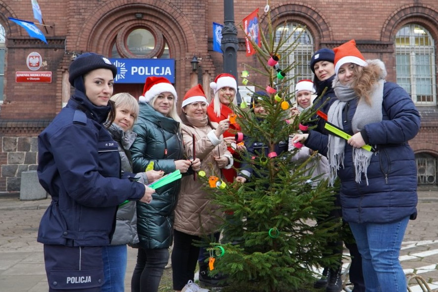 Osoby ubierające choinkę w odblaski przed KMP w Olsztynie