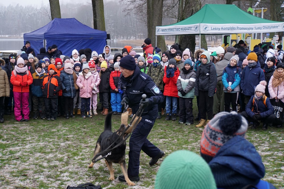 Pokaz obrony przed atakiem psa. Dzieci wokół policjanta z psem