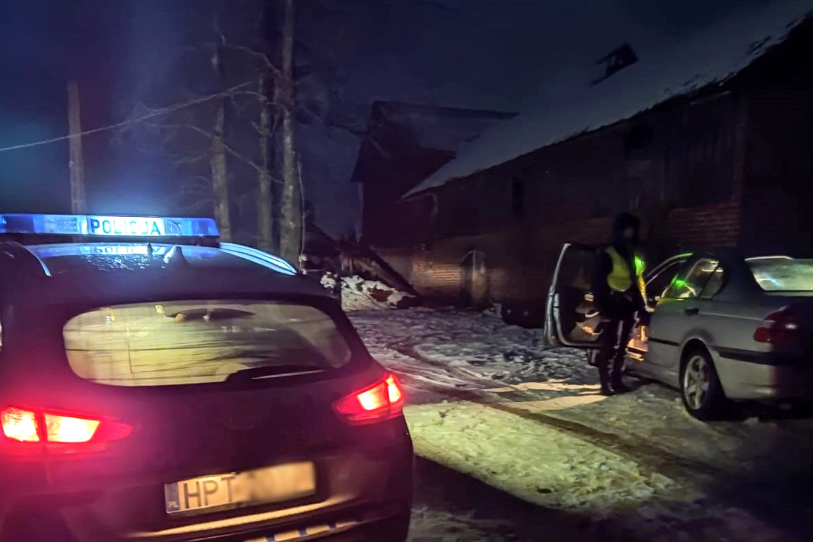 Radiowóz i zatrzymane do kontroli BMW, zaparkowane na śniegu