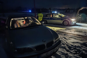 Radiowóz i zatrzymane do kontroli BMW, zaparkowane na śniegu