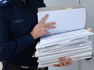 Policjant trzymający teczkę z aktami w dłoniach