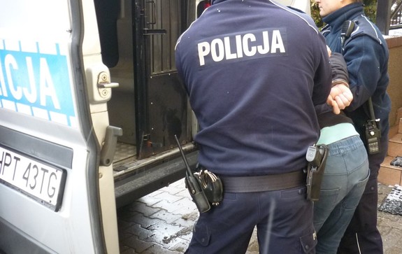 Zatrzymany mężczyzna prowadzony przez policjantów do radiowozu