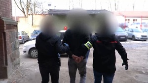 Zatrzymany mężczyzna prowadzony przez policjantów do radiowozu