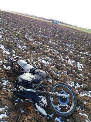 Wywrócony motocykl leżący w polu