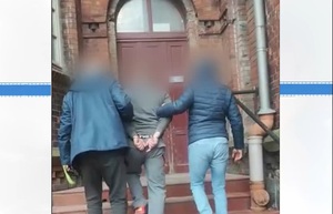 Policjanci prowadzą osobę zatrzymaną