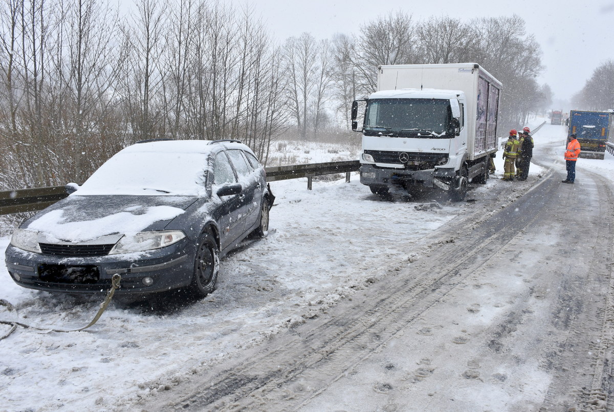 pojazd osobowy i ciężarowy stojące na drodze i przy pojeździe ciężarowym służby