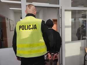 policjant prowadzi osobę zatrzymaną