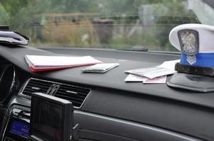 Policyjna czapka i dokumenty leżące na desce rozdzielczej w radiowozie