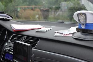 Policyjna czapka i dokumenty leżące na desce rozdzielczej w radiowozie