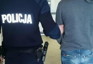 policjant prowadzi osobę zatrzymaną