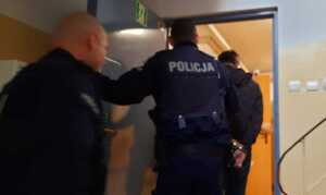 Policjanci prowadzą osobę zatrzymaną