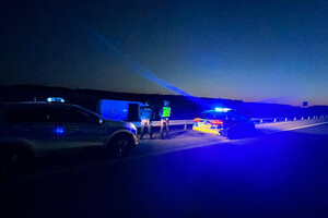 Radiowozy i zatrzymany bus stojące na poboczu drogi. W centralnym punkcie widoczni są policjanci