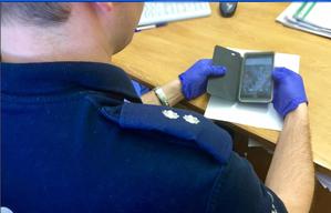 policjant trzyma w ręku telefon komórkowy