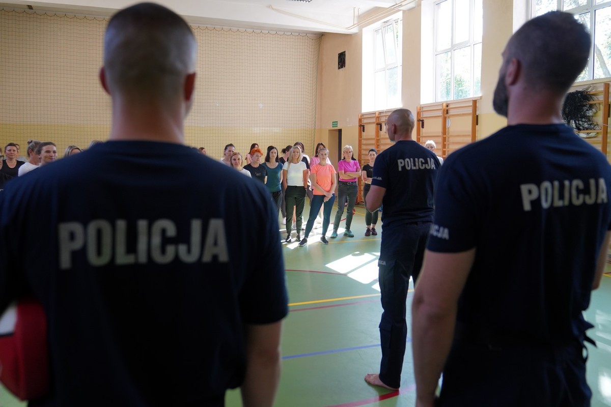 Uczestnicy szkolenia z samoobrony dla kobiet. Policjanci i kobiety na sali gimnastycznej