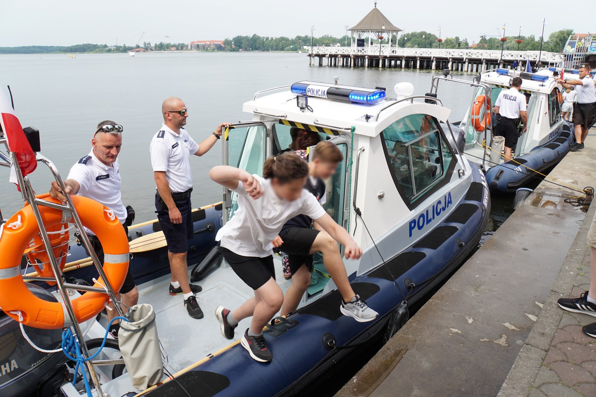Uczestnicy spotkania na bulwarze przy łódkach policyjnych