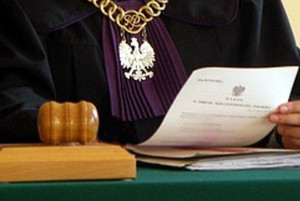 Sylwetka sędziego za stołem i sędziowski młotek leżący na biurku