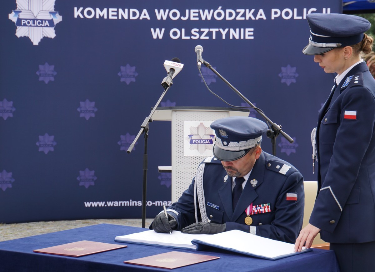 Komendant Wojewódzki Policji w Olsztynie składa podpis w księdze pamiątkowej