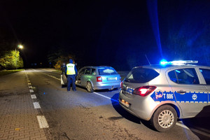 Miejsce zatrzymania mężczyzny. Radiowóz i samochód osobowy oraz policjant stojący na drodze