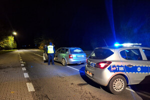 Miejsce zatrzymania mężczyzny. Radiowóz i samochód osobowy oraz policjant stojący na drodze