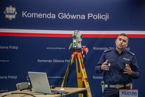 Policjant na tle baneru Komendy Głównej Policji