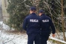 Policjanci podczas kontroli miejsca gdzie mogą przebywać bezdomni. Idą zaśnieżoną ścieżką