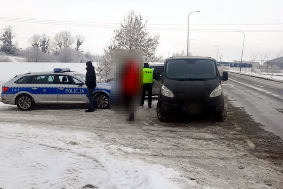 Miejsce kontroli drogowej. Radiowóz i zatrzymany samochód oraz policjanci na zaśnieżonym poboczu drogi