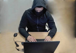Zamaskowana osoba przy laptopie