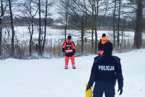 Policjanci i strażacy na miejscu zdarzenia nad jeziorem