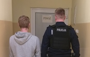 Policjant prowadzi osobę zatrzymaną