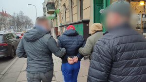 Policjanci prowadzą osobę poszukiwaną