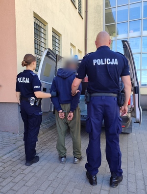 Policjanci prowadzą osobę poszukiwaną
