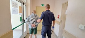Policjant prowadzi osobę zatrzymaną