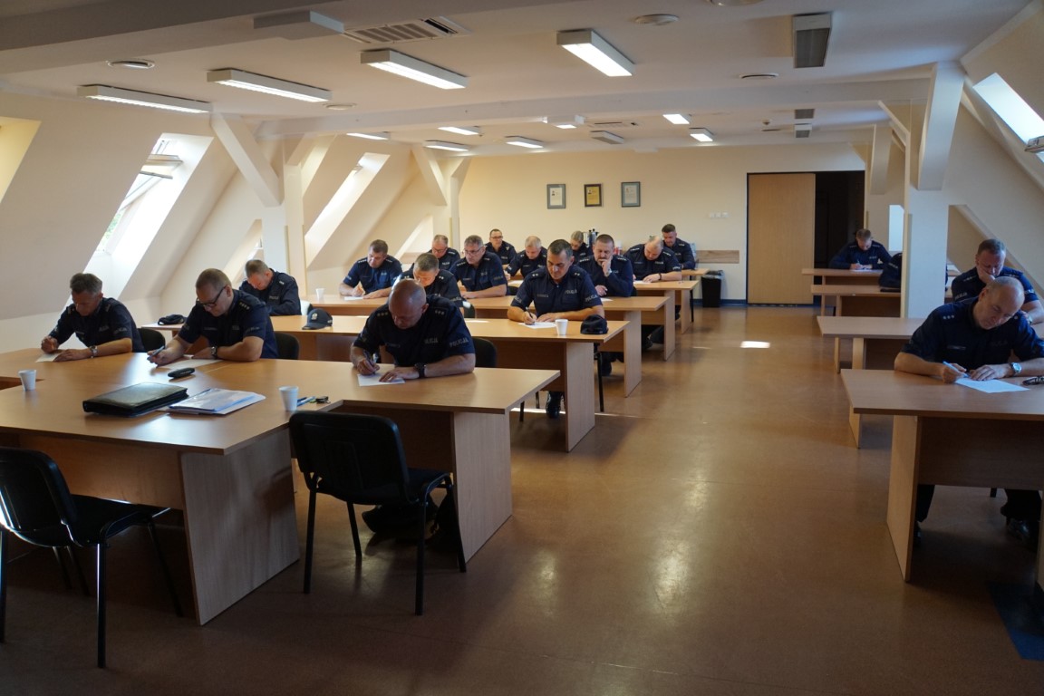 Zdjęcie przedstawia uczestników turnieju - umundurowanych policjantów podczas rozwiązywania testu.