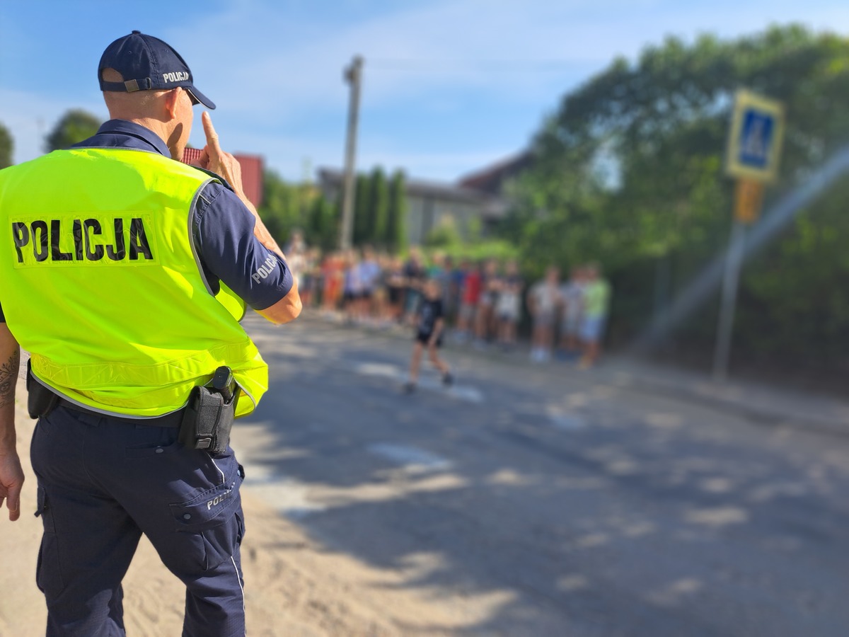 Zdjęcie przedstawia policjanta oraz w tle dzieci.