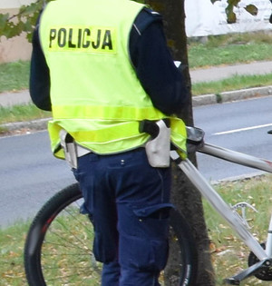 Zdjęcie przedstawia fragment policjanta i roweru.