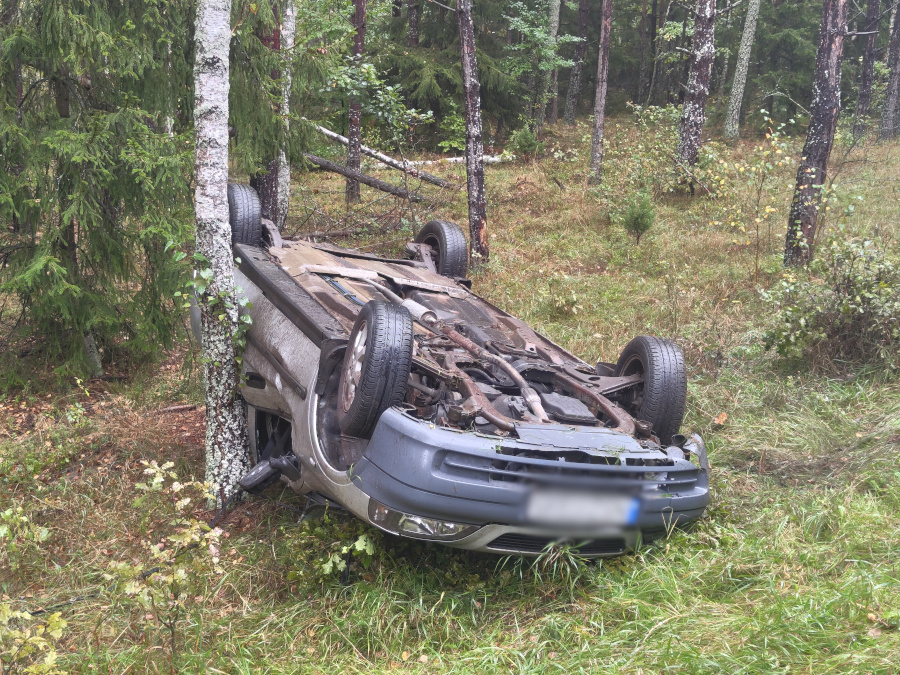 Zdjęcie przedstawia auto, które dachowało w przydrożnym rowie.